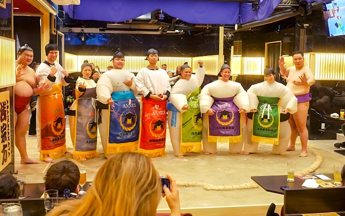 Visitors posing with sumo wrestlers at Asakusa Sumo Club, Tokyo.