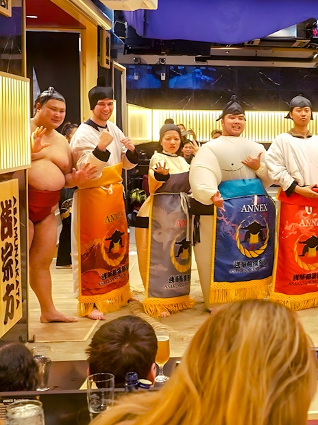 Visitors posing with sumo wrestlers at Asakusa Sumo Club, Tokyo.