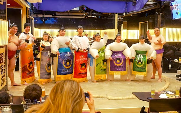 Visitors posing with sumo wrestlers at Asakusa Sumo Club, Tokyo.