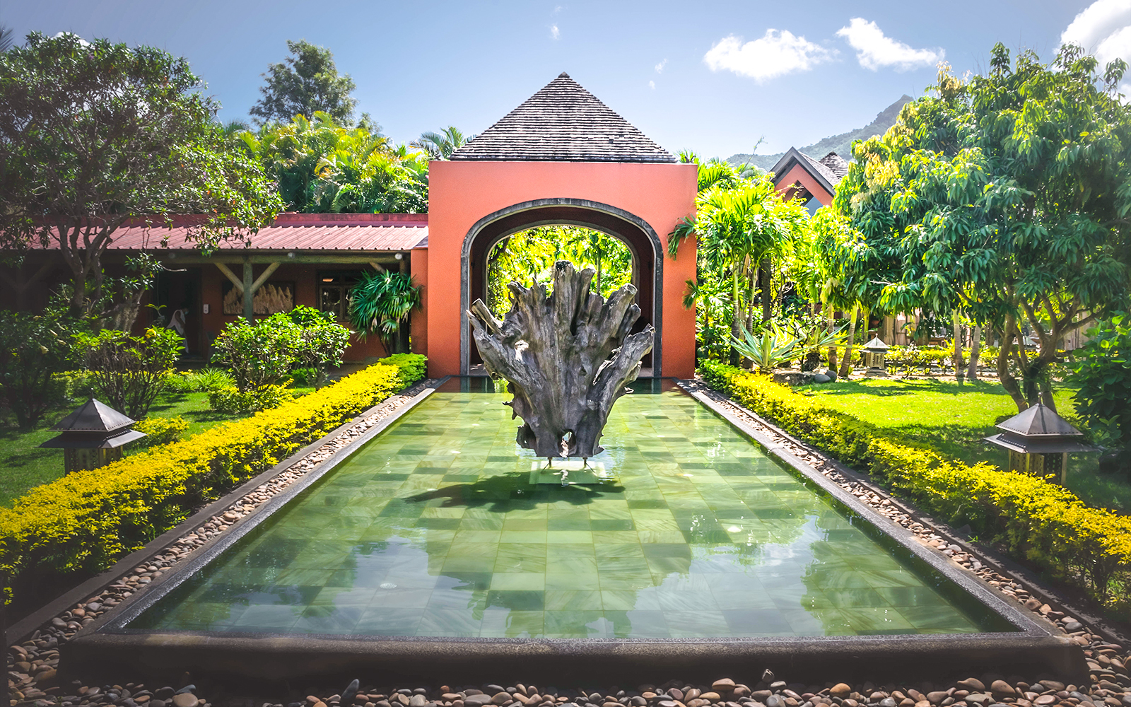Rhumerie Chamarel entrance with water feature and lush gardens, Mauritius.