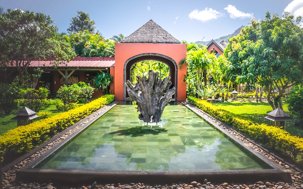 Rhumerie Chamarel entrance with water feature and lush gardens, Mauritius.