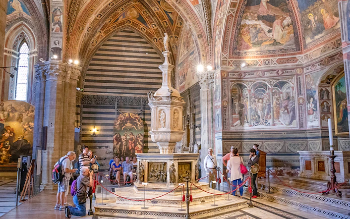 Tourists inside Siena Cathedral admiring frescoes and ornate architecture, Italy.