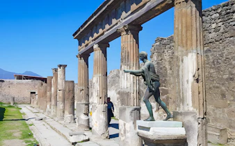 Ancient columns and statue at Pompeii ruins, Italy.