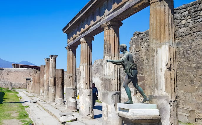 Ancient columns and statue at Pompeii ruins, Italy.