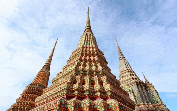Colorful spires of Wat Pho temple in Bangkok under a clear sky.