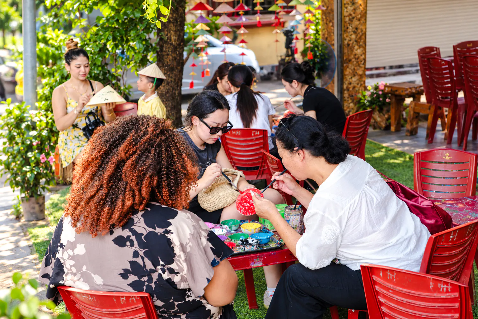 Visitors painting traditional crafts at a Hanoi village during a cultural tour.