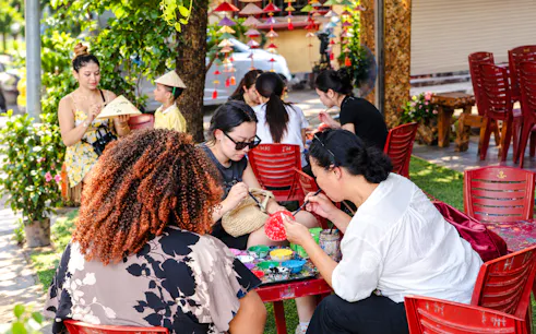 Visitors painting traditional crafts at a Hanoi village during a cultural tour.