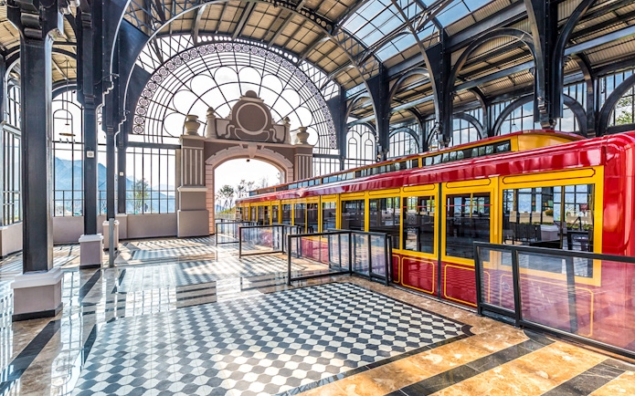Red and yellow train inside Sun World Fansipan Legend station with arched glass roof.