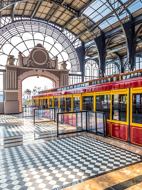 Red and yellow train inside Sun World Fansipan Legend station with arched glass roof.