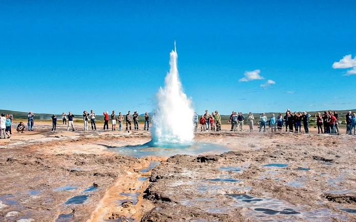 Geyser eruption at Strokkur, Iceland, with tourists observing during Golden Circle tour.