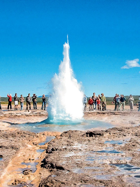 Geyser eruption at Strokkur, Iceland, with tourists observing during Golden Circle tour.