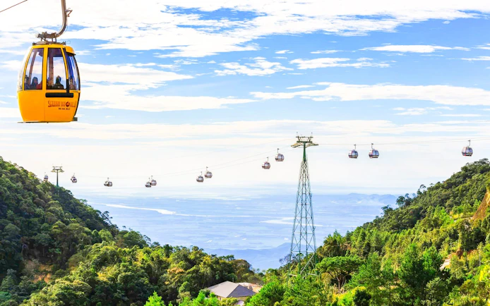 Cable cars at Sun World Ba Na Hills in Da Nang, Vietnam, with lush green hills.