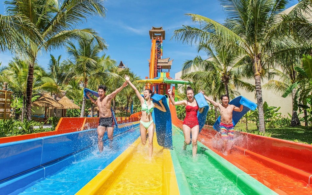 Guests enjoying water slide at VinWonders with palm trees in the background.