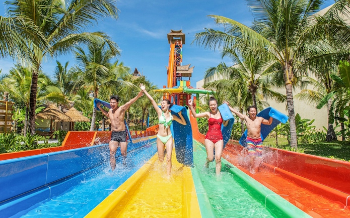 Guests enjoying water slide at VinWonders with palm trees in the background.