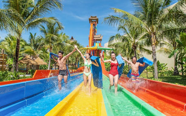Guests enjoying water slide at VinWonders with palm trees in the background.