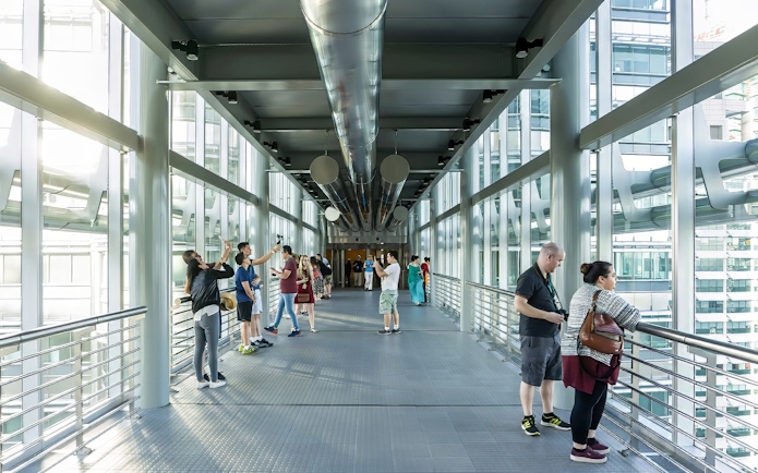 Visitors on the SkyBridge at Petronas Twin Towers, Kuala Lumpur, taking photos and enjoying views.