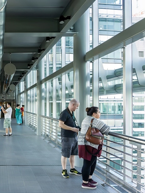 Visitors on the SkyBridge at Petronas Twin Towers, Kuala Lumpur, taking photos and enjoying views.
