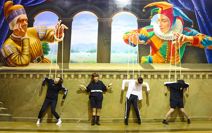 Visitors pose as marionettes in front of a puppet-themed mural at Art in Paradise Pattaya.