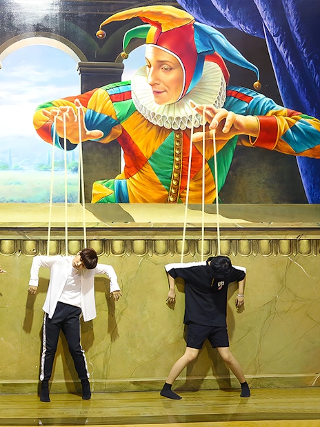 Visitors pose as marionettes in front of a puppet-themed mural at Art in Paradise Pattaya.
