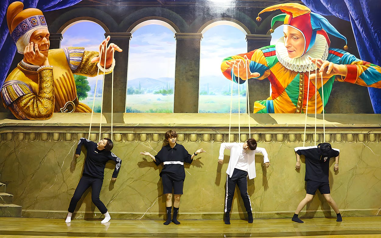 Visitors pose as marionettes in front of a puppet-themed mural at Art in Paradise Pattaya.