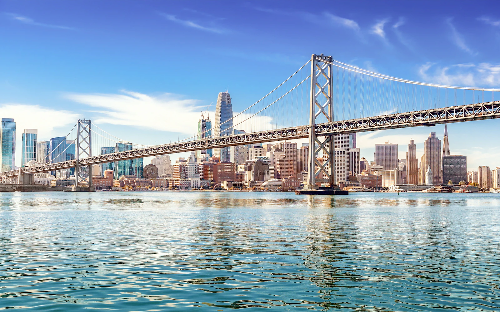 Downtown San Francisco skyline with Oakland Bay Bridge on a sunny day.