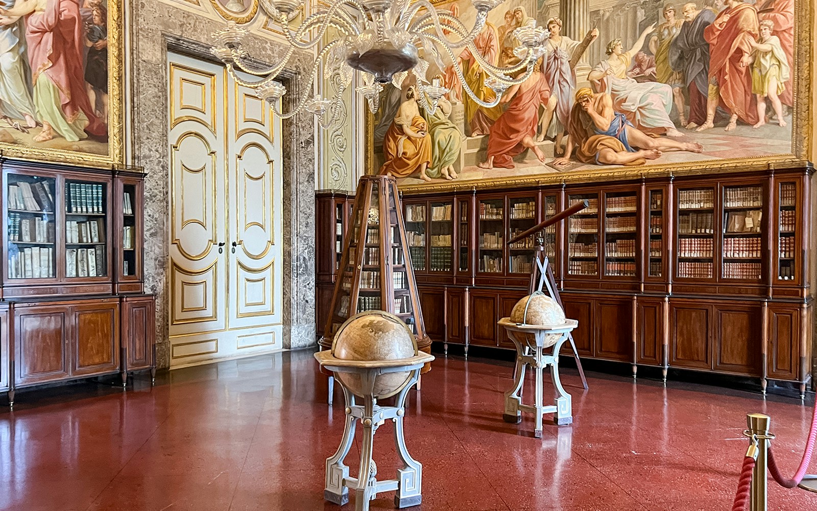 Royal Palace of Caserta library with rows of antique books and ornate wooden shelves.