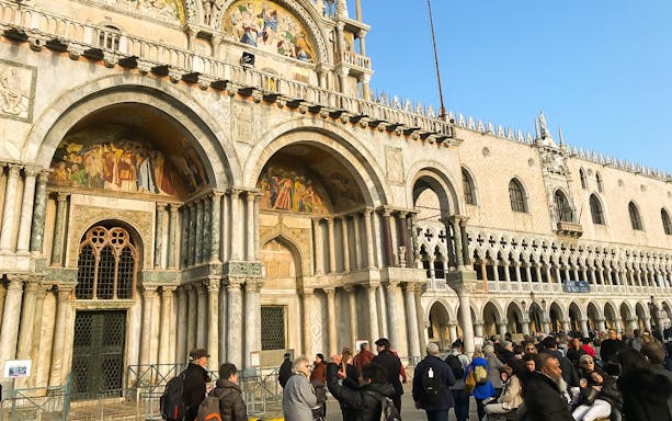 St. Mark's Basilica facade with tourists in Venice during a full-day tour from Lake Garda.