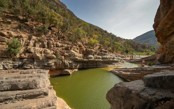 Rocky landscape with green water pools in Paradise Valley, surrounded by trees and hills.