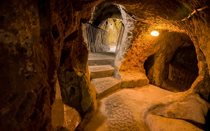 Derinkuyu underground cave city passage with stone steps and rock walls.