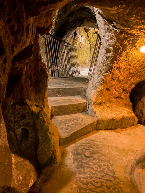Derinkuyu underground cave city passage with stone steps and rock walls.