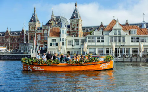 Guests enjoying Aperol Spritz Cruise on a canal in Amsterdam with historic buildings in the background.