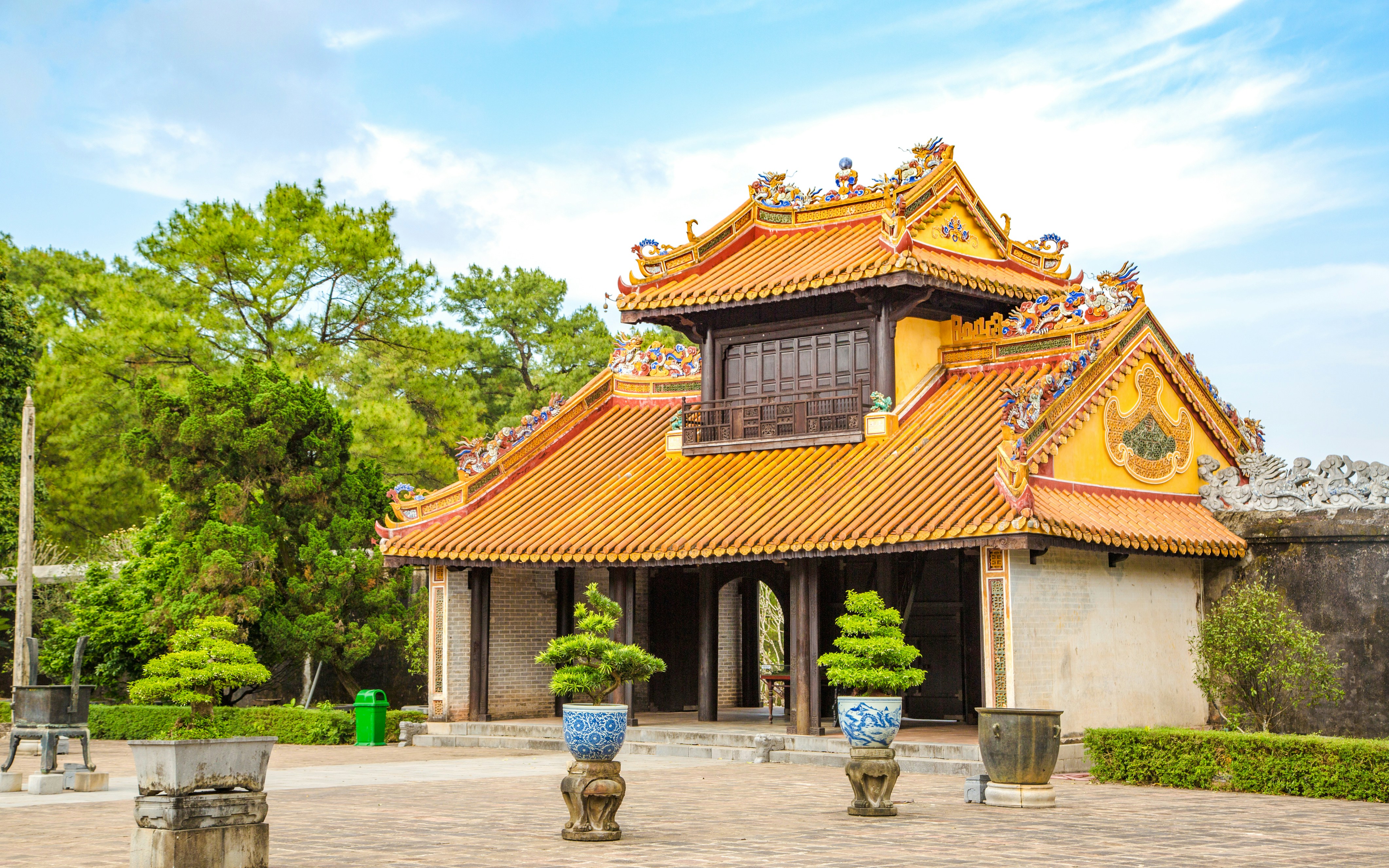 Tomb of Tu Duc pavilion with ornate roof and potted plants in Hue, Vietnam.