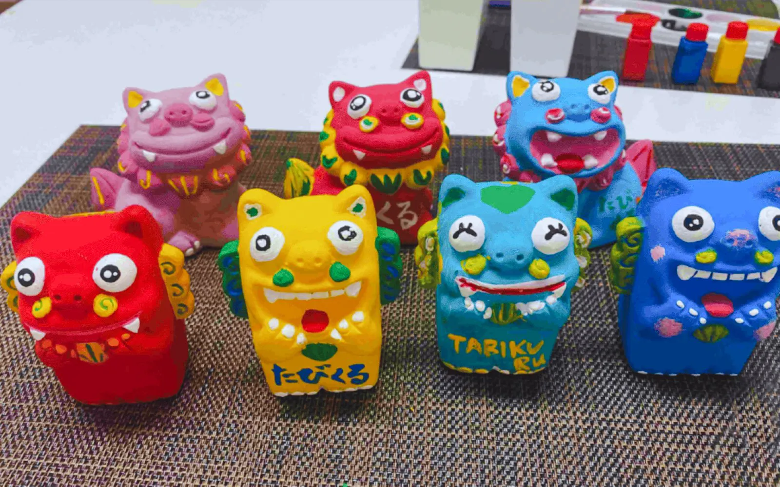 Colorful terracotta Shisa statues from Okinawa displayed on a mat.