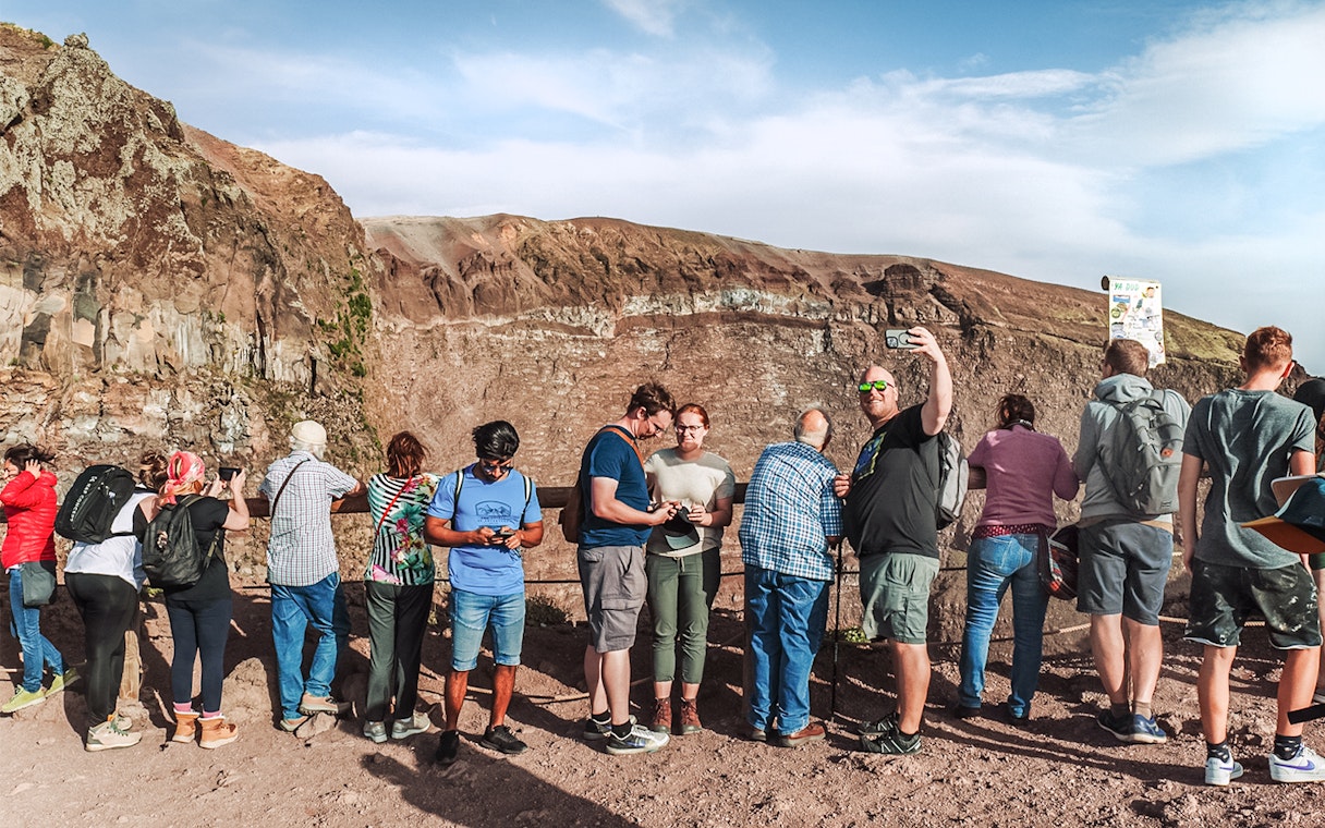 Tourists taking photos at the crater of Mount Vesuvius, Italy.