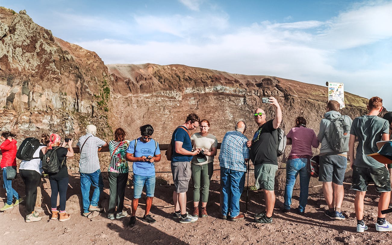 Tourists taking photos at the crater of Mount Vesuvius, Italy.