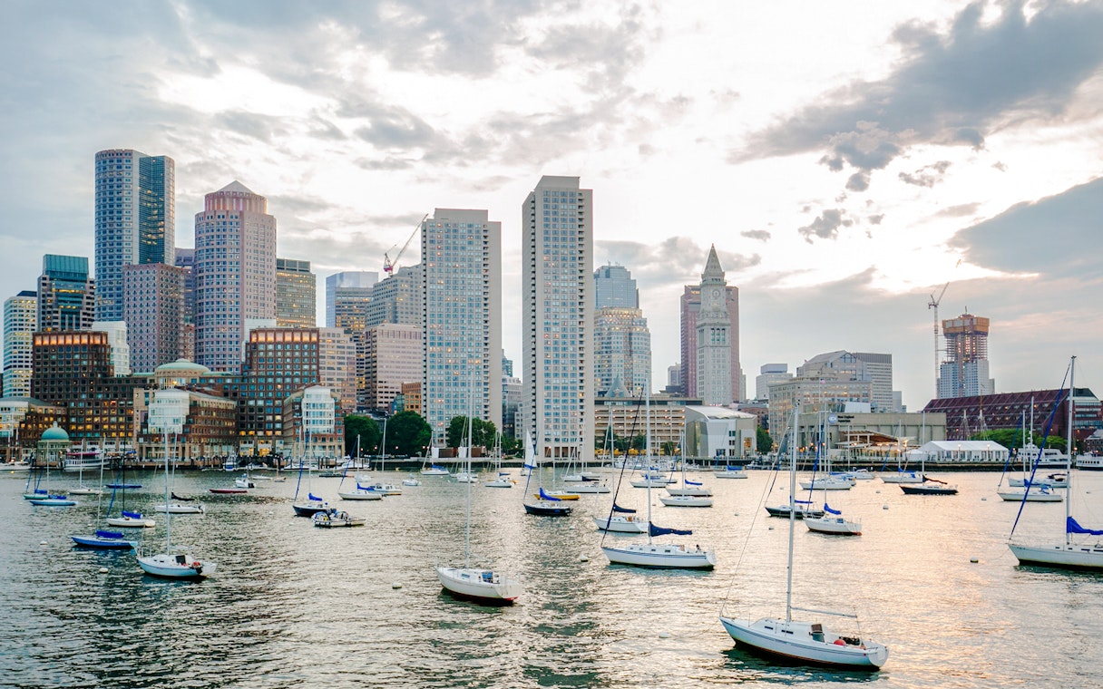 Boston Harbor with sailboats and city skyline in the background.