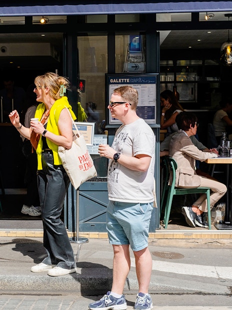 People outside Galette Café during Emily in Paris Food Tour, holding drinks and tote bags.