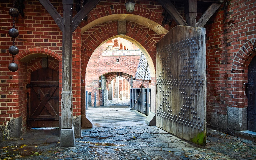 Malbork Castle gate with brick arches and wooden door, part of Gdańsk tour.