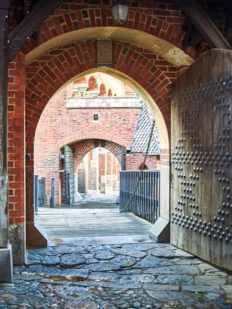 Malbork Castle gate with brick arches and wooden door, part of Gdańsk tour.