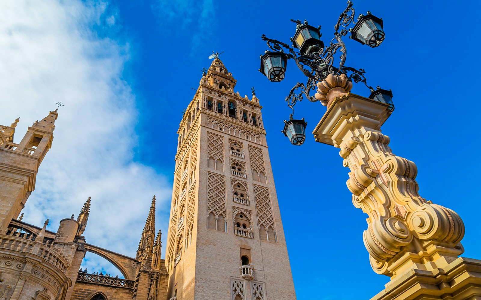 Giralda tower and ornate lamp post at Seville Cathedral, Spain.
