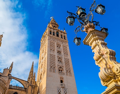 Giralda tower and ornate lamp post at Seville Cathedral, Spain.