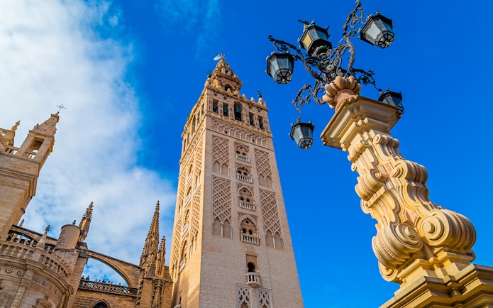 Giralda tower and ornate lamp post at Seville Cathedral, Spain.