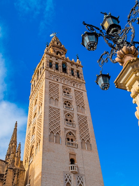 Giralda tower and ornate lamp post at Seville Cathedral, Spain.