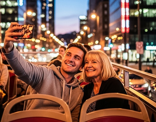Tourists taking a selfie on a hop-on hop-off bus in a city at night.