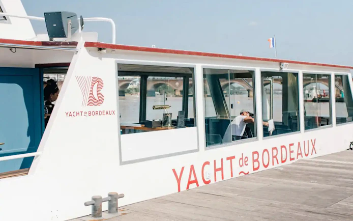 Yacht docked for Bordeaux River Cruise with bridge in background.