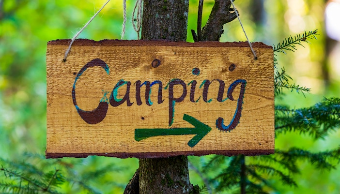 Milford Sound Cascade Creek campsite with tents and lush forest backdrop.