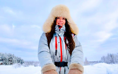 Guests enjoying a husky ride in snowy landscape, wearing warm winter clothing.