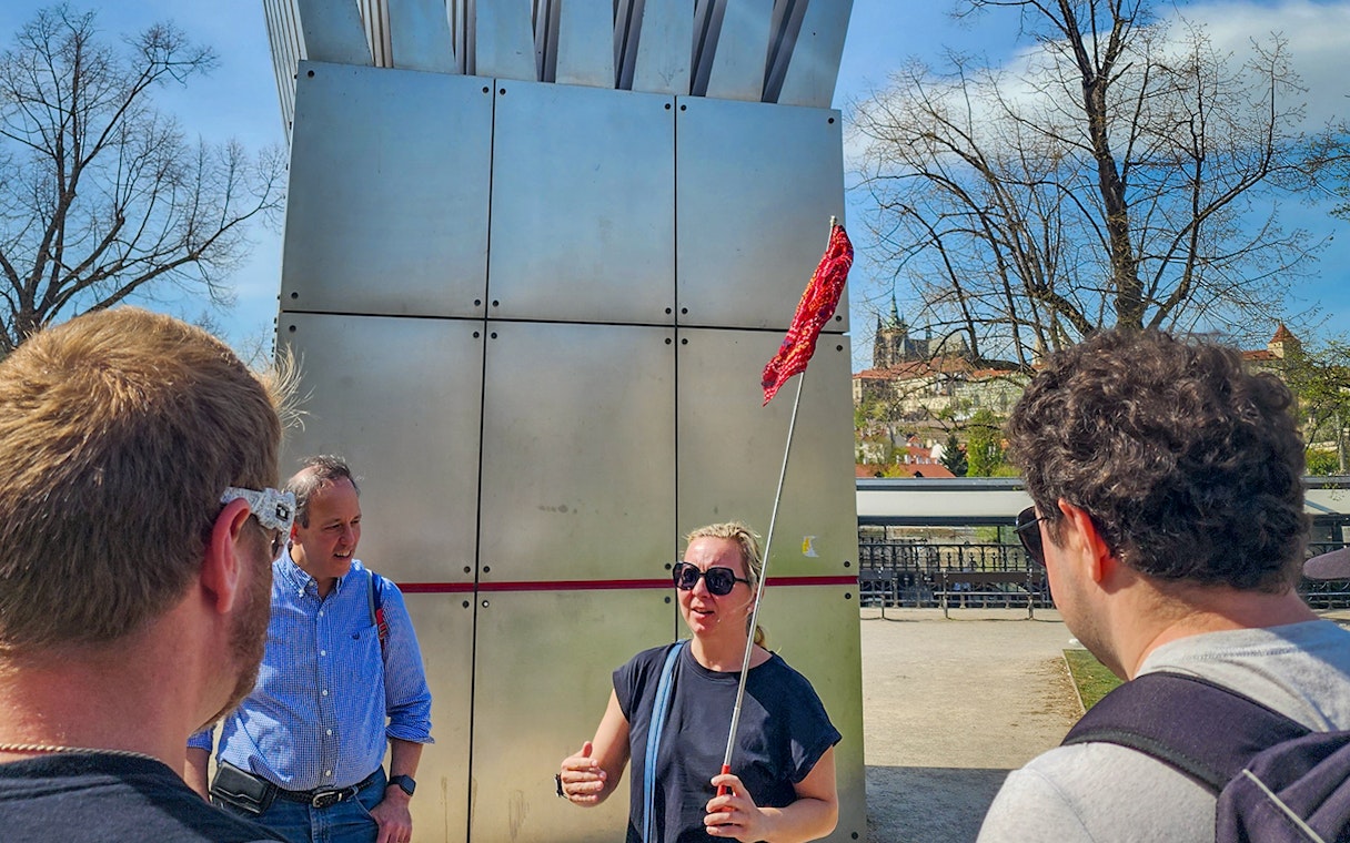 Tour guide leading a group near Prague Castle with city view in background.