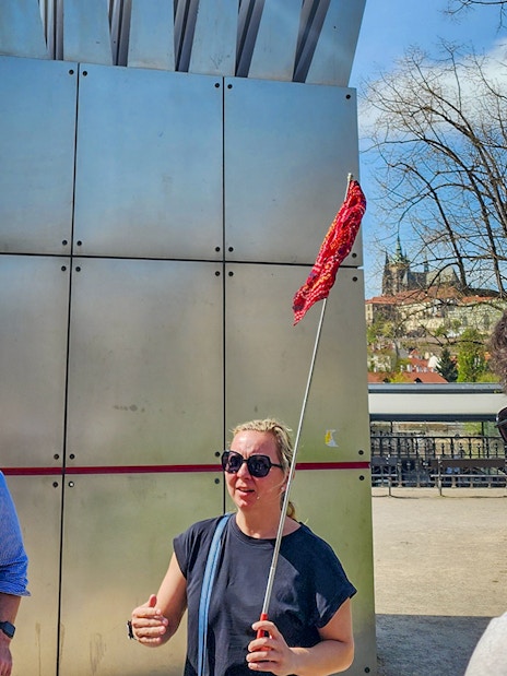 Tour guide leading a group near Prague Castle with city view in background.