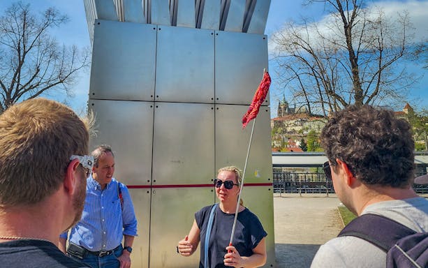 Tour guide leading a group near Prague Castle with city view in background.